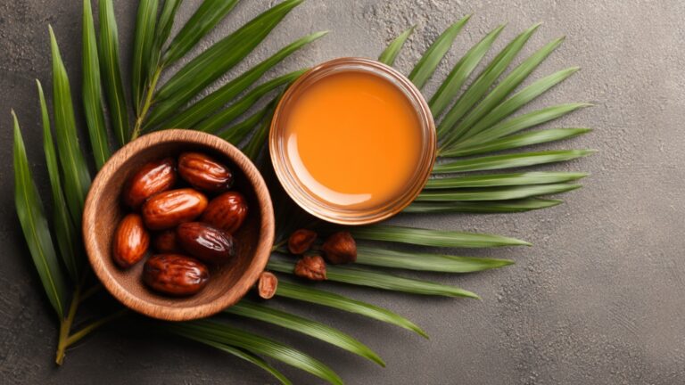 Činija sa plodovima palme i posuda sa svežim palminim uljem, položene na zelenim listovima palme